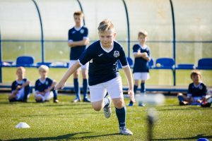 ćwiczenia wytrzymałościowe chłopców podczas letniego obozu piłkarskiego