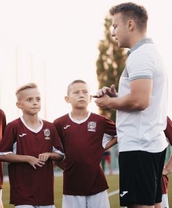 Trener tłumaczy ćwiczenie piłkarskie chłopcu