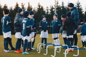 Chłopcy na obozie zimowym piłkarskim słuchają trenera