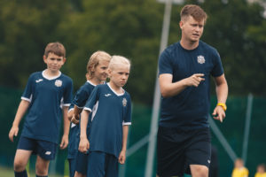 Trener pokazuje ćwiczenia dzieciom na obozie piłkarskim