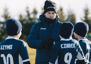 trener rozmawia z dziećmi na obozie piłkarskim zimą