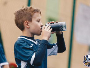 Chłopiec pije wode na meczu piłkarskim