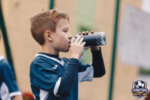 Chłopiec pije wode na meczu piłkarskim