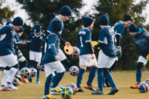 dzieci w strojach piłkarskich prowadzą piłki obozie piłkarskim Champions Camp
