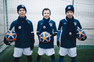 trójka chłopców na obozie zimowo sportowym z piłką w ręku