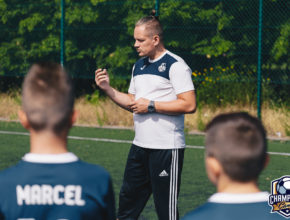 trener tłumaczący dzieciom taktykę piłkarską podczas odprawy